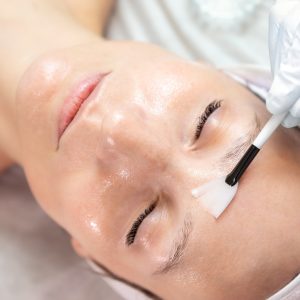 Close-up beautician doctor hand making anti-age procedure apply peeling acid young female person